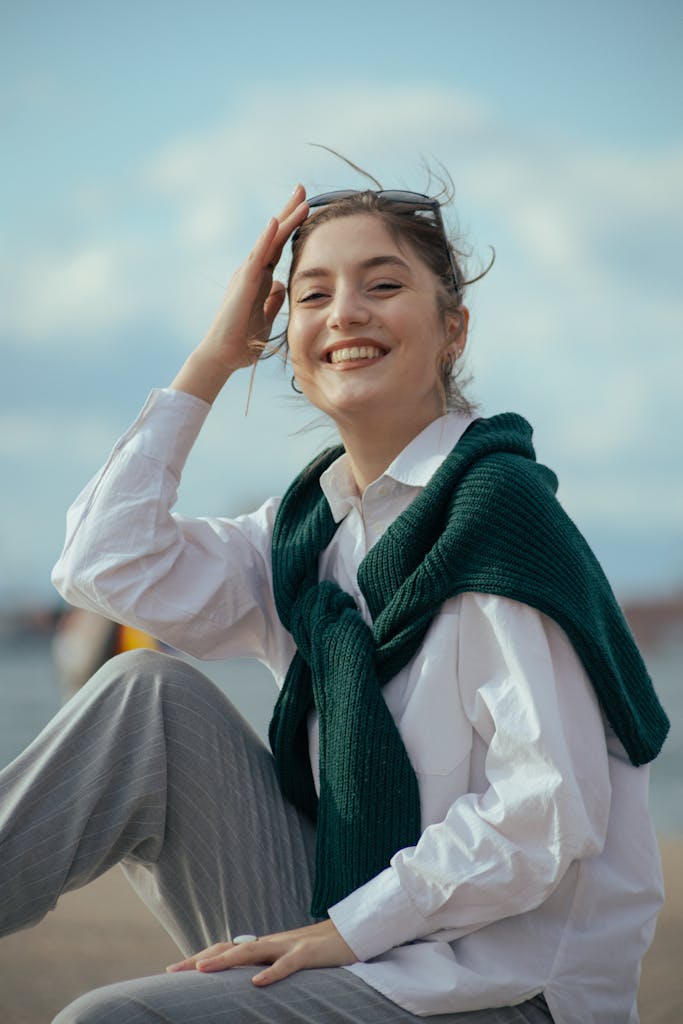 Cheerful woman sitting outdoors with a sweater and bright smile.